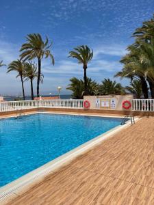 a swimming pool with palm trees and a fence at Casa Limon in Cartagena