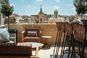 a balcony with chairs and a table and a view of a city at Romègas Hotel in Valletta +11 photos