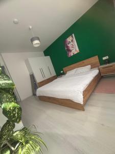 a bedroom with a bed with a green wall at Apartament Bella in Târgu-Mureş