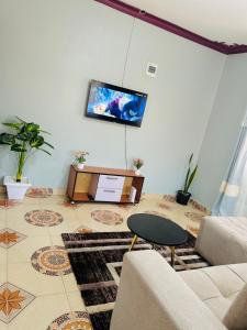 a living room with a couch and a tv on the wall at Zarex homes 1 in Mbale