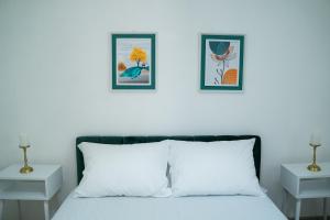 a white bedroom with two pictures above a bed at Vikendica Forest Mansion Surčin in Progar +14 photos
