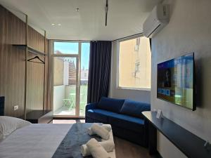 a bedroom with a bed and a couch and a tv at SOLs Center Rooms in Tirana