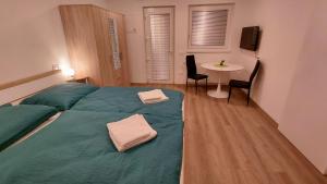 a bedroom with a green bed with a table and chairs at Apartment and Studios Jelovca & Wellness in Radovljica