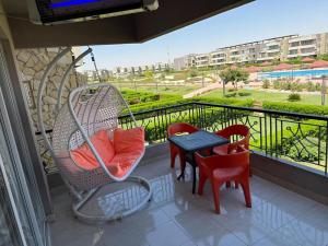 a balcony with a swing and a table and chairs at Marina Blu Blumar Chalet in Ain Sokhna