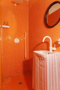 an orange tiled bathroom with a shower and a sink at Plumard in Arles