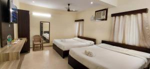 a hotel room with two beds and a mirror at Jazz Inn in Tiruvallūr +11 photos
