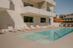 a swimming pool with chairs and a building at Almar Suites Daimús in Daimuz