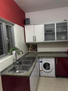 a kitchen with a sink and a washing machine at Espaço Acolhedor in Luanda