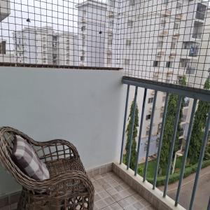 a rattan chair on a balcony with a view of a building at Espaço Acolhedor in Luanda