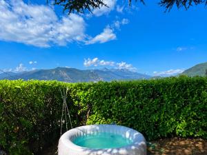 a bath tub in front of a hedge with mountains in the background at FUGA ROMANTICA - Panoramica in Almese