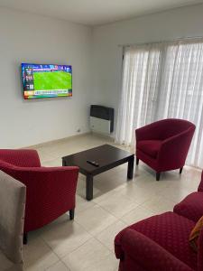 a living room with two chairs and a table and a tv at Heart Viedma in Viedma