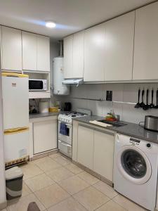 a kitchen with white cabinets and a washing machine at Heart Viedma in Viedma