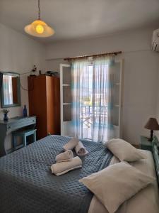 a bedroom with two towels on a bed with a window at Deilino - Sunset Studio in Amorgos