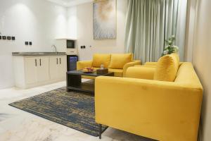 a living room with two yellow couches and a table at لحظات للشقق المخدومة in Jeddah