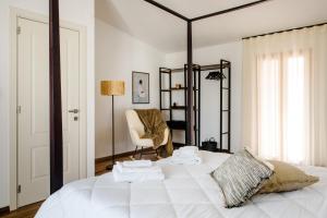 a bedroom with a large white bed with a chair at Dimore Abruzzo - Borgo 27 in Celano
