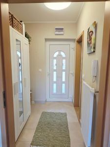 a hallway with a white door and a rug at SilvaBlau Apartment Hévíz in Hévíz