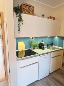 a kitchen with white cabinets and a sink at SilvaBlau Apartment Hévíz in Hévíz
