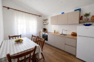 a kitchen with a table with a bowl of fruit on it at Seafront apartments Marija with terrace and mooring in Rogoznica