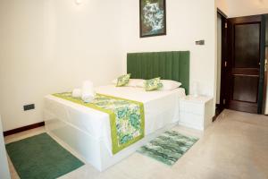 a bedroom with a white bed with a green headboard at Regal Retreat in Mahawatta +7 photos