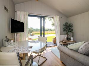 a living room with a table and a couch at Leafy Oaks Cabin in Much Wenlock
