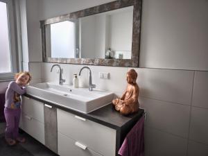 a little girl standing next to a sink in a bathroom at Zeitlos in Stutensee +10 photos