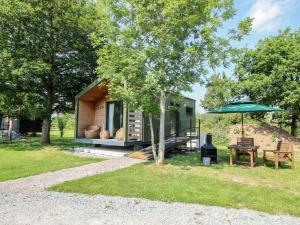 a tiny house with a picnic table and an umbrella at Leafy Oaks Cabin in Much Wenlock