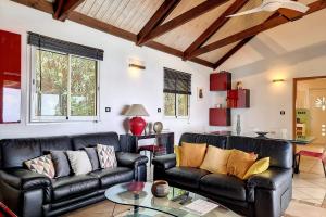 a living room with two leather couches and a table at Villa Perle de lOcéan Piscine - Clim in Les Avirons