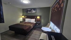 a small hotel room with a bed and a table at Knights Inn Bracebridge in Bracebridge