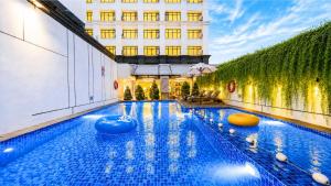 a large swimming pool with blue water in a building at Metro Park View Hotel Kota Lama Semarang in Semarang