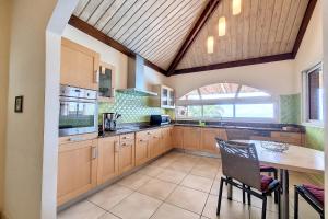 a kitchen with wooden cabinets and a table and a window at Villa Perle de lOcéan Piscine - Clim in Les Avirons