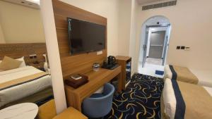 a hotel room with a bed and a desk with a television at Nuzul Nebras Al Madinah in Medina