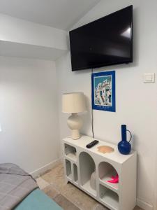 a room with a white table with a tv on the wall at Santorin étoilé- hyper centre in Sanary-sur-Mer