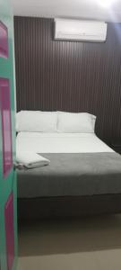 a bed with white sheets and pillows in a room at Hostal Johnnier Macao Punta Cana in Punta Cana