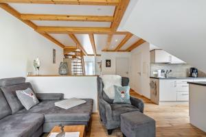 a living room with a couch and chairs and a kitchen at Ferienwohnungen Schwarzwaldtraum in Unterkirnach