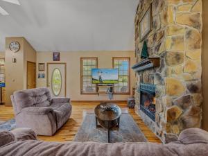 a living room with a stone fireplace and a tv at Blue Badger Cottage -Wifi, Fire Pit, Fireplace, Screen Porch, Game Room, King Bed, Grill in Morton Grove +34 photos
