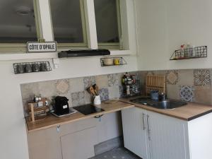 a small kitchen with white cabinets and a sink at Au Kaycedra in Calais