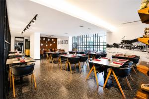 a restaurant with tables and chairs in a room at Metro Park View Hotel Kota Lama Semarang in Semarang