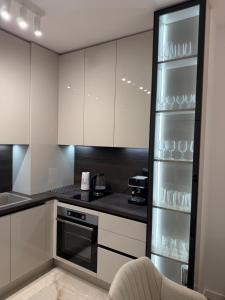 a kitchen with white cabinets and a refrigerator with glasses at Resident park apartment in Plovdiv +3 photos