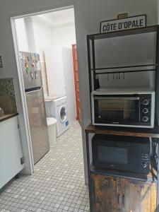 a kitchen with a microwave and a refrigerator at Au Kaycedra in Calais