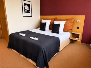 a hotel room with a large bed with two plates on it at Axis Hotel Brussels Airport in Kortenberg