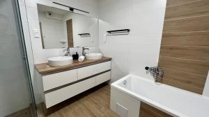 a bathroom with two sinks and a tub and a mirror at Rezidex Apartmanház in Szeged
