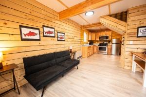 a living room with a black couch in a cabin at Halibut Haven, Cabin 7 at Lower Kenai Lodge in Kenai