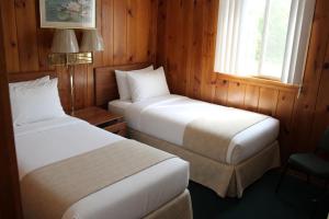 zwei Betten in einem Zimmer mit Holzwänden und Fenstern in der Unterkunft Paddle Inn in Ely