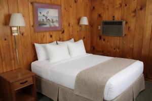 ein großes weißes Bett in einem Zimmer mit Holzwänden in der Unterkunft Paddle Inn in Ely