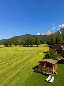 a field with two white chairs and a house at Alpenperle in Ramsau am Dachstein