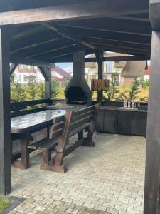 a wooden bench sitting under a pavilion with an outdoor oven at Cazare Băile Figa -The Home DRM in Beclean