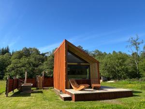 a small wooden house with a deck and chairs at Ben Nevis Basecamp in Torlundy