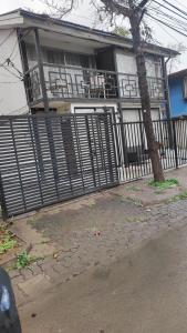 a house with a fence and a tree in front of it at Casa 3 dormitorios estacionamiento Heriberto Ortiz in Santiago
