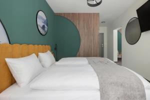 a bedroom with a large white bed with a clock on the wall at Santa Christina Mountain Resort in Świeradów-Zdrój