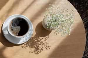 a cup of coffee and a vase of flowers on a table at Santa Christina Mountain Resort in Świeradów-Zdrój